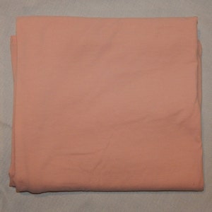 May include: A folded piece of peach-colored fabric. The fabric is smooth and has a slight sheen.