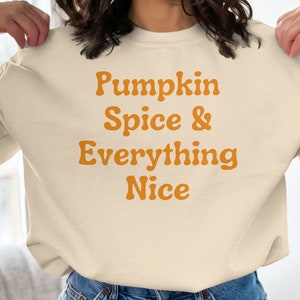 May include: A cream-coloured sweatshirt with the text "Pumpkin Spice & Everything Nice" in orange.