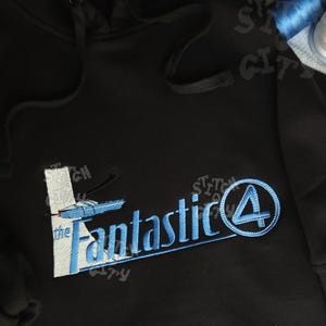 May include: Black hooded sweatshirt with a blue embroidered design that says "the Fantastic 4" with a blue number 4.