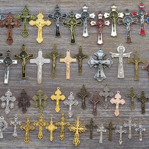 Puede incluir: Una colecci&oacute;n de varios colgantes de crucifijo de metal con diversos dise&ntilde;os, acabados y tama&ntilde;os. El surtido incluye tonos de metal plateado, dorado, bronce, cobre y colores, cada uno representando a Jes&uacute;s en la cruz.