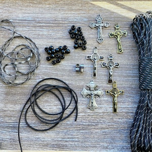 Puede incluir: Un kit de manualidades que incluye un manojo de paracord moteado en blanco y negro, un rollo de cord&oacute;n negro s&oacute;lido, varias cuentas redondas peque&ntilde;as de color negro, dos cuentas espaciadoras met&aacute;licas y seis crucifijos de metal en tonos plata y bronce.