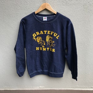 May include: A navy blue long-sleeved sweatshirt with a yellow graphic of two dancing bears and the text "GRATEFUL HUNTER".