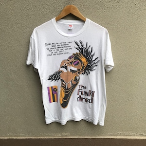 May include: White t-shirt with a colorful illustration of a person with dreadlocks and the text "Before man, god, or time itself there was rhythm - The endless hypnotic rhythm that is the root and core of life itself - From this rhythm came... The Funki dired"