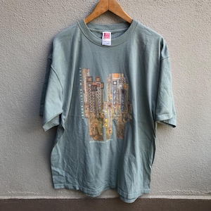 May include: A green t-shirt with a graphic print of a building design by Frank Lloyd Wright. The text "FRANK LLOYD WRIGHT" is printed vertically on the left side of the graphic.