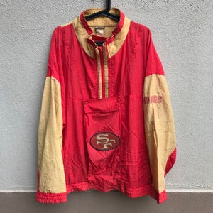 Op de afbeelding: Een rode en beige vintage windbreaker jack met een San Francisco 49ers logo op de voorkant en de tekst "49ers" op de mouw.