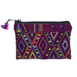 May include: A small purple zippered pouch with a colorful geometric pattern. The pouch has a black zipper and a tassel.