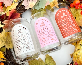 May include: Three glass jars with lids, each featuring a white label with the text "Cold Brew Coffee" and details about the coffee, including "Freshly Brewed", "Roast", and "Est. Every Morning". The labels are on a pink, orange, and white background.