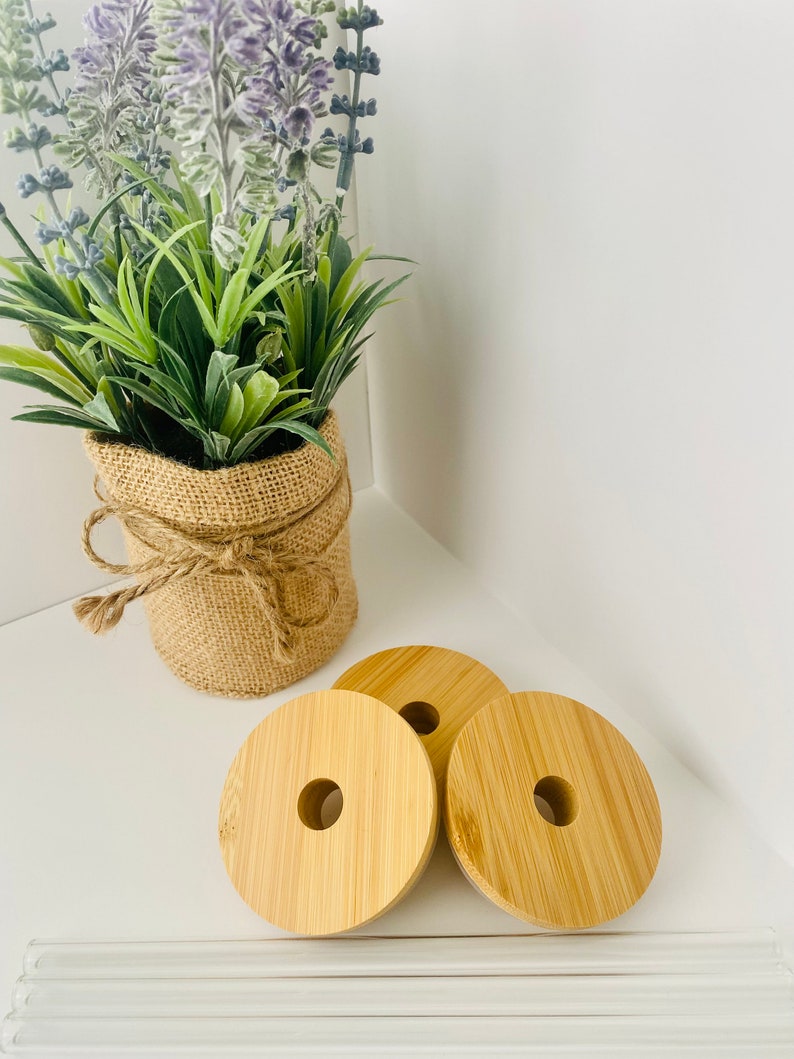 May include: Three natural wood round bottle stoppers with a hole in the center. The stoppers are on a white surface with a bundle of clear glass straws.