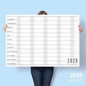 May include: A large white wall calendar for the year 2028 featuring a horizontal grid layout. The months from January to December are listed on the left side, with days of the month arranged in columns across the page. The year 2028 is printed in large black font in the bottom right corner.