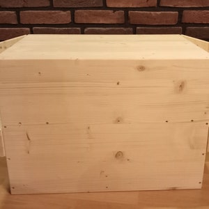 Könnte beinhalten: Eine Holzkiste mit zwei Regalen an den Seiten. Die Kiste ist aus hellem Holz und hat eine natürliche Oberfläche.