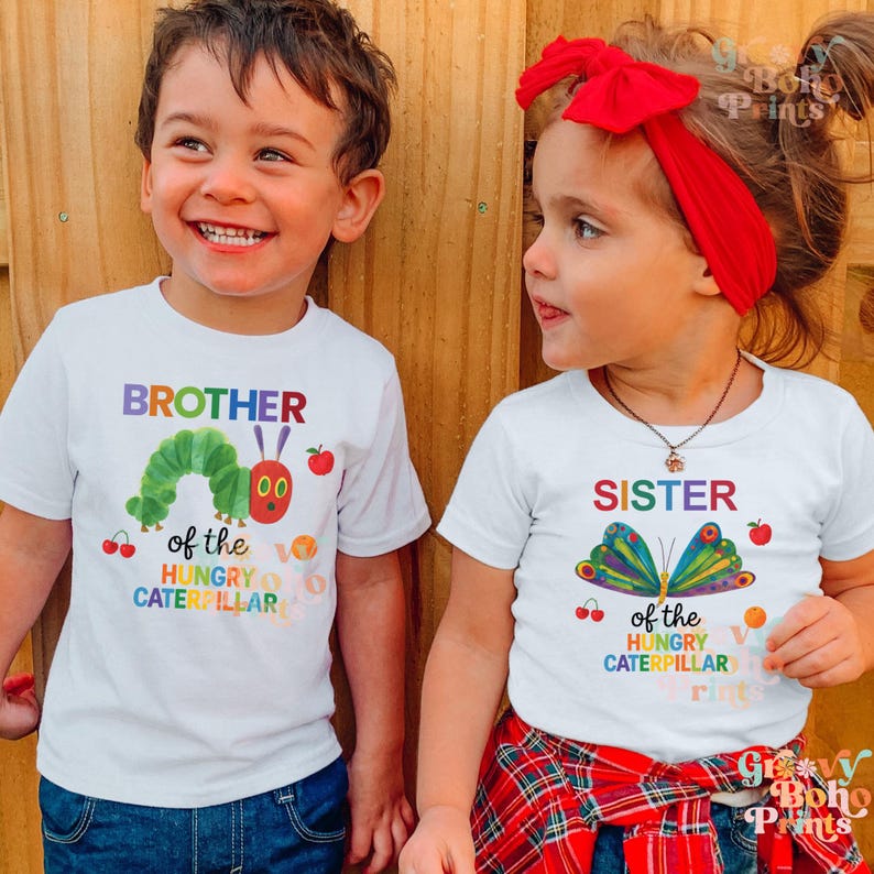 May include: Two children wearing white t-shirts with colorful graphics. One shirt says "BROTHER" with a caterpillar design, the other says "SISTER" with a butterfly. Both shirts feature text from "The Very Hungry Caterpillar" book.