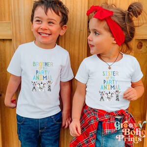 Puede incluir: Dos ni&ntilde;os con camisetas blancas con tem&aacute;tica de animales de fiesta. La camiseta del ni&ntilde;o dice "Hermano del animal de fiesta" y la camiseta de la ni&ntilde;a dice "Hermana del animal de fiesta". Ambas camisetas muestran una cebra, un elefante y una jirafa con sombreros de fiesta.