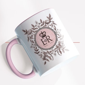 May include: A white ceramic mug with a pink handle and rim. The mug features a floral design with a crown and the letters "ER" inside a circular emblem. The text "1926-2022" is below the emblem.