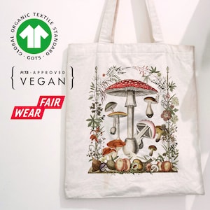May include: White canvas tote bag with a colorful illustration of mushrooms and foliage. The bag has the text "Global Organic Textile Standard GOTS" and "PETA-Approved Vegan" printed on it.