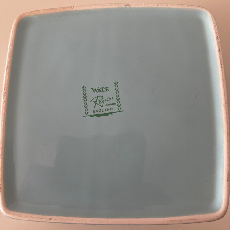Puede incluir: Un plato cuadrado de cer&aacute;mica azul claro con un sello verde de Wade Regency London England en la parte inferior.