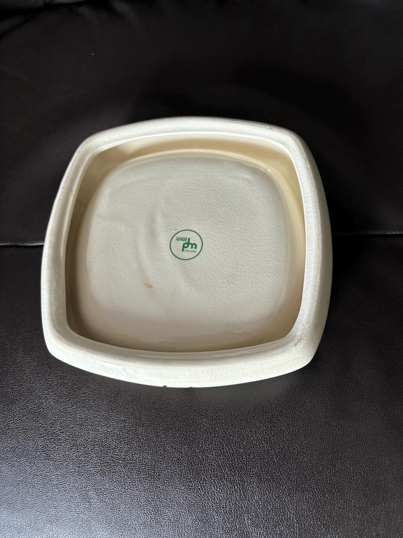May include: White square ceramic dish with a raised rim and a green logo that says "bio pm" on the bottom.