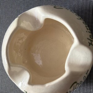 May include: White ceramic ashtray with green lettering that reads "Happy Holidays".