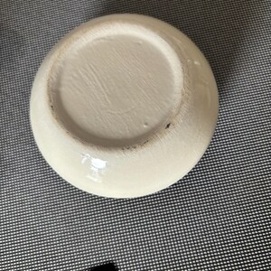 May include: The bottom of a white ceramic bowl with a smooth, glossy finish.
