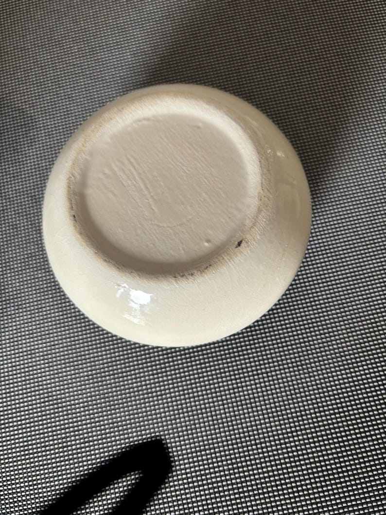 May include: The bottom of a white ceramic bowl with a smooth, glossy finish.
