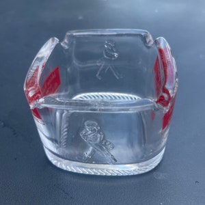 May include: A clear glass ashtray with a red and white label that says "Johnnie Walker Red Label" and a raised image of a man walking with a cane.