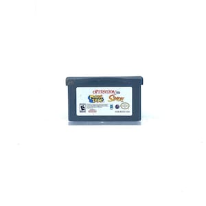 May include: A black Game Boy Advance game cartridge with a colorful label. The label features the text "Operation:  Mouse Trap  Simon" and a cartoon mouse. The game is rated E for Everyone by the ESRB.
