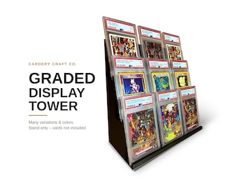May include: A black tiered display tower holding nine graded trading cards in protective plastic cases. The text on the left reads CARDERY CRAFT CO. GRADED DISPLAY TOWER. Many variations & colours. Stand only – cards not included.