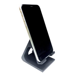 May include: A black phone stand with a smartphone resting on it. The phone is black with a white border and a black screen.