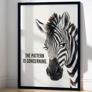 Könnte beinhalten: Ein gerahmter Wandkunstdruck mit einer realistischen Illustration eines Zebra-Kopfes mit schwarzen und weißen Streifen auf weißem Hintergrund. Der Text "THE PATTERN IS CONCERNING." ist in schwarzen, serifenlosen Großbuchstaben links aufgedruckt.