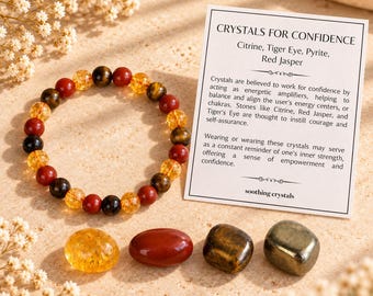 May include: A beaded bracelet made of citrine, tiger eye, pyrite, and red jasper stones. Beside it are four loose tumbled stones of the same minerals and a white card with the text Crystals for Confidence, listing the stone types.