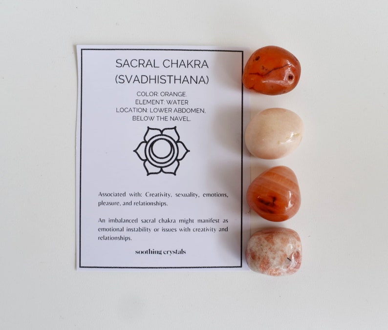 May include: Set of four orange carnelian tumbled stones with a card that reads "Sacral Chakra (Svadhisthana)" with information about the chakra.  The card also says "Color: Orange, Element: Water, Location: Lower Abdomen, Below the Navel. Associated with: Creativity, sexuality, emotions, pleasure, and relationships. An imbalanced sacral chakra might manifest as emotional instability or issues with creativity and relationships. soothing crystals"