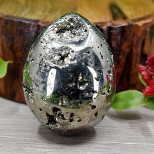 May include: A silver pyrite egg with a smooth, shiny surface. The egg is made of natural crystal and has a unique, organic shape.