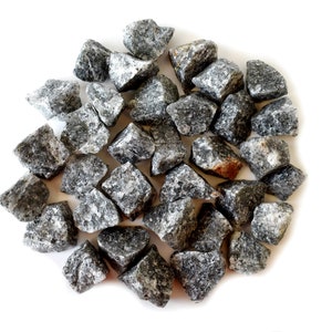 May include: A close-up of a pile of small, gray and white stones. The stones are irregularly shaped and have a rough texture.