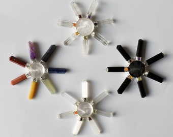 Può includere: Tre set di cristalli rotanti per chakra con cristalli di quarzo trasparente, ametista e ossidiana nera. Ogni set ha una base circolare con sette pietre colorate.
