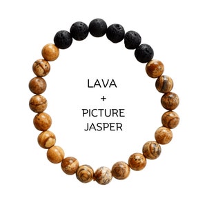 May include: A bracelet made with brown and black beads. The brown beads are made of picture jasper and the black beads are made of lava rock. The bracelet has the text "LAVA + PICTURE JASPER" printed on it.