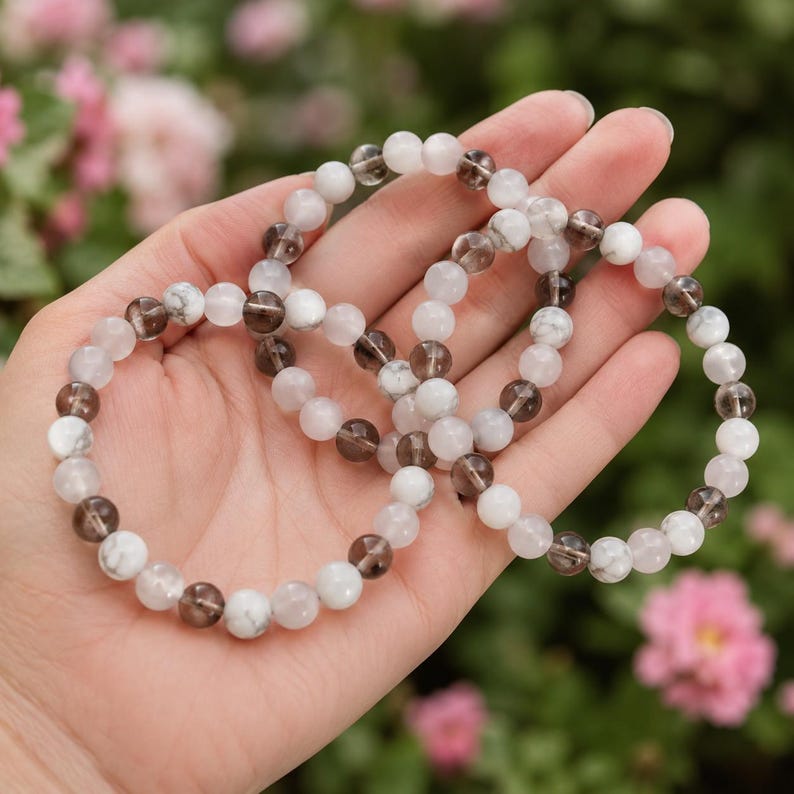 Puede incluir: Dos pulseras el&aacute;sticas de cuentas con cuentas redondas alternas de cuarzo ahumado transl&uacute;cido y piedra blanca opaca veteada. Las cuentas son pulidas y lisas, dispuestas en un patr&oacute;n repetitivo para crear un dise&ntilde;o circular para la mu&ntilde;eca.