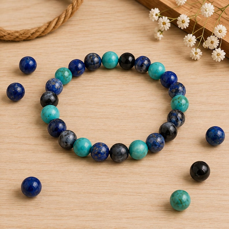 May include: A circular beaded bracelet featuring a repeating pattern of round polished stones in shades of deep blue, turquoise, and black. Several loose matching beads are scattered around the bracelet, which is arranged in a circle.