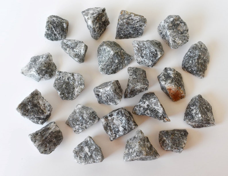 May include: A collection of 20 grey and black tumbled stones. The stones are various sizes and shapes, with some having a slightly rough texture.