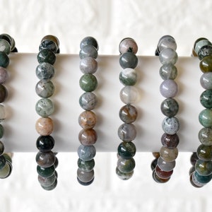 May include: Seven green, brown, and white agate stone bracelets with round beads.