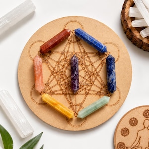 Könnte beinhalten: Ein rundes Holzbrett mit einem lasergravierten Metatron-Würfel-Muster, belegt mit sieben doppelseitigen Kristallspitzen in Rot, Blau, Violett, Dunkelblau, Gelb, Hellgrün und Orange, die in einer hexagonalen Form angeordnet sind.