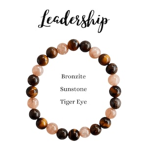 May include: A bracelet made of tiger eye, sunstone, and bronzite beads. The bracelet is brown, orange, and pink. The word "Leadership" is written above the bracelet.