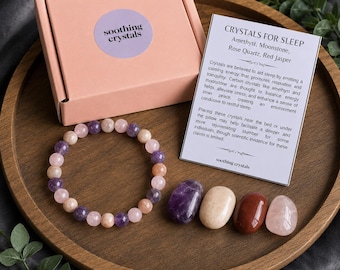 May include: A pink cardboard box with a circular label reading soothing crystals, a beaded bracelet with purple, pink, and peach stones, four tumbled crystals, and an informational card titled Crystals for Sleep listing amethyst, moonstone, rose quartz, and red jasper.