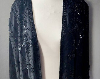 May include: A black sequined jacket with a long, open front and long sleeves. The jacket is made of a soft, flowing fabric and is adorned with delicate sequins.