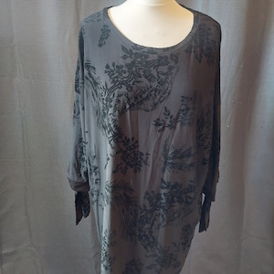 May include: A black tunic with a floral pattern. The tunic has a round neckline and long sleeves with a tie detail at the cuffs.