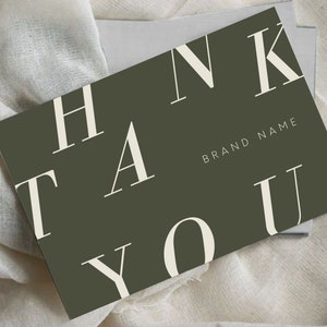 Könnte beinhalten: Eine dunkelgrüne Dankeskarte mit weißer Beschriftung, die in großen, stilisierten Buchstaben "THANK YOU" lautet. Der Text "BRAND NAME" ist in kleineren weißen Buchstaben unter dem Gruß gedruckt.