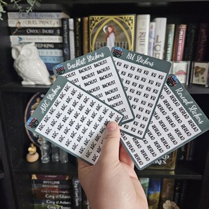 May include: A set of six stickers with different designs. The stickers are all rectangular and have a green background with white text. The text on the stickers includes "Backlist Stickers", "ARC Stickers", "Reread Stickers", and "KU Stickers".