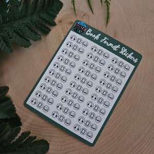 May include: A sheet of green sticker paper with white outlines of various book format icons. The icons include a book, a tablet, and headphones. The text "Book Format Stickers" is printed in white on the sheet.