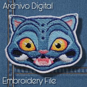 Könnte beinhalten: Gestickter Aufnäher mit einem stilisierten blauen Katzenkopf mit großen gelb-schwarzen Augen, einer rosa Nase und offenem Mund. Der Aufnäher hat einen weißen Rand und den Text "Archivo Digital" und "Embroidery File".