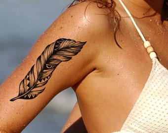 May include: A woman with long blonde hair wearing a white crocheted bikini top. She has a black feather tattoo on her upper arm.