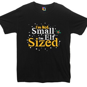 Può includere: Maglietta nera con testo bianco che dice "I'm Not Small, I'm Elf Sized" con un piccolo ramo di agrifoglio rosso e verde.