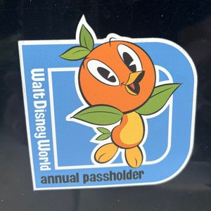 Pu&ograve; includere: Adesivo blu e bianco con un personaggio di uccello arancione e il testo "Walt Disney World annual passholder".